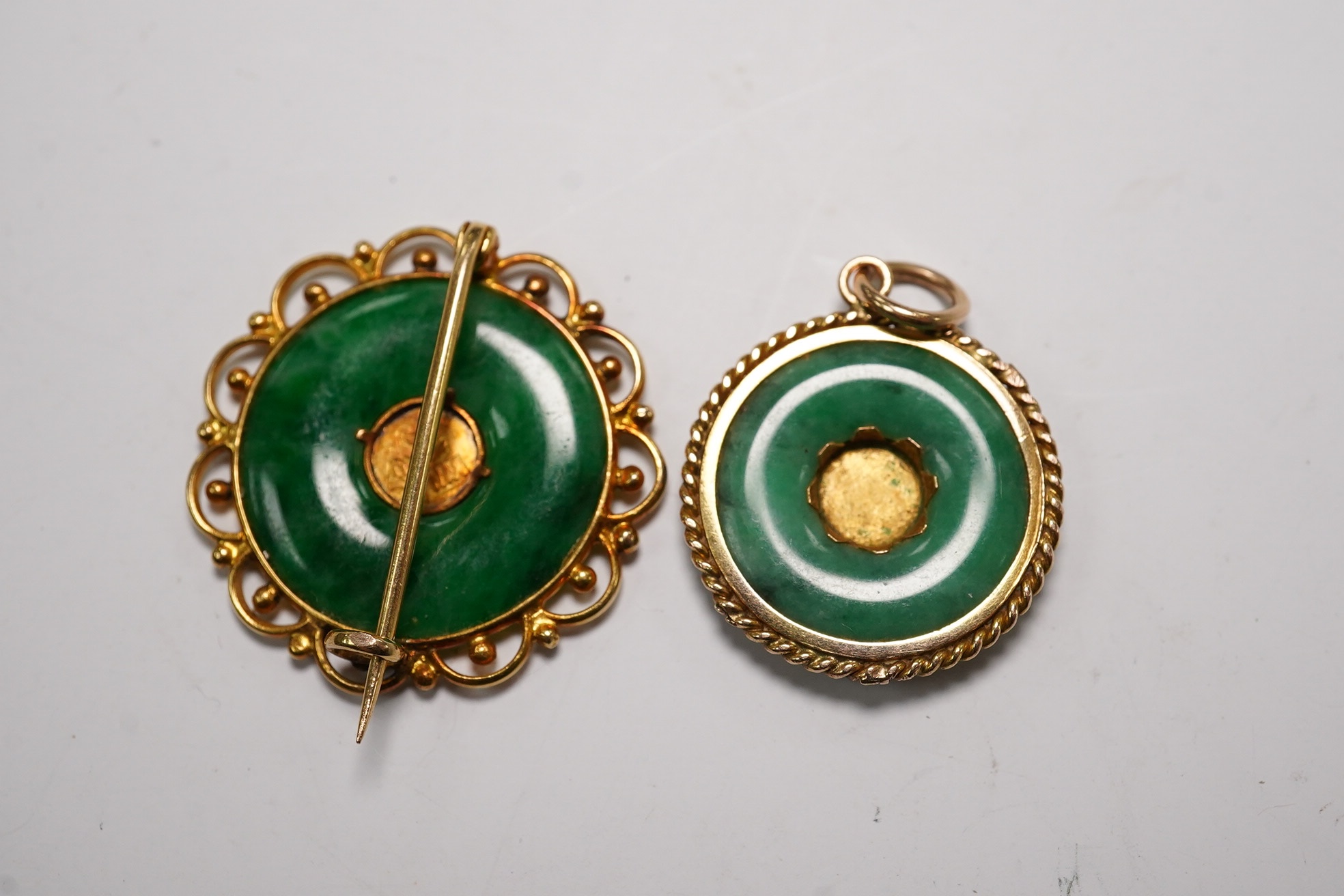 A Chinese 18k and jade set circular brooch, 23mm and a similar yellow metal and jade set pendant, gross weight 5.3 grams. Condition - fair